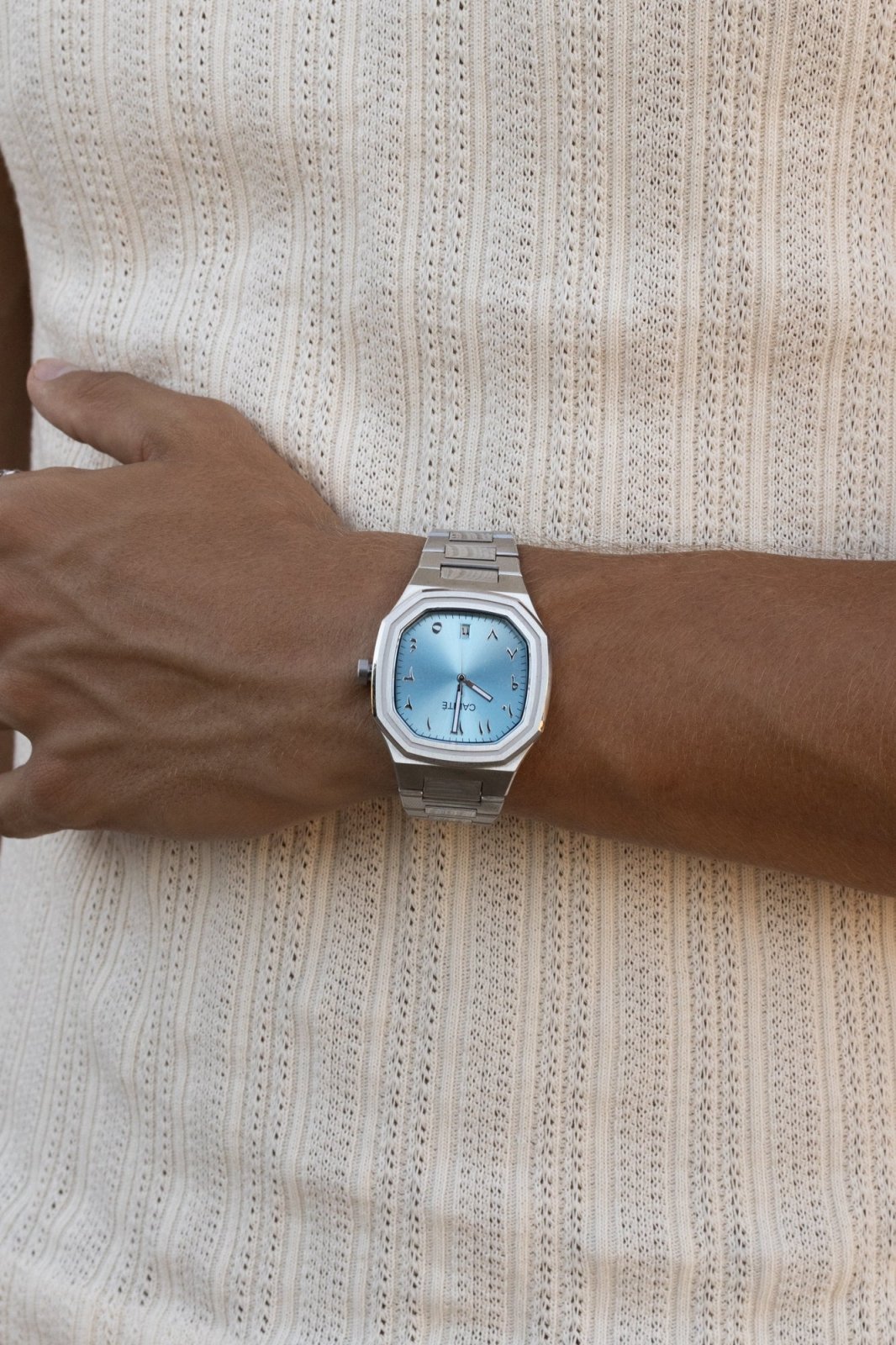Watch on a wrist against a ribbed knit top