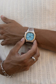 Fingers on the watch against a ribbed knit top