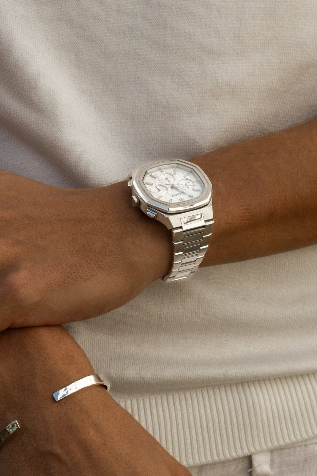 Watch on a wrist against a white T-shirt