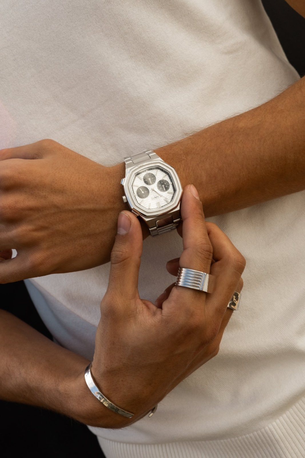 Hands adjusting the watch over a white T-shirt