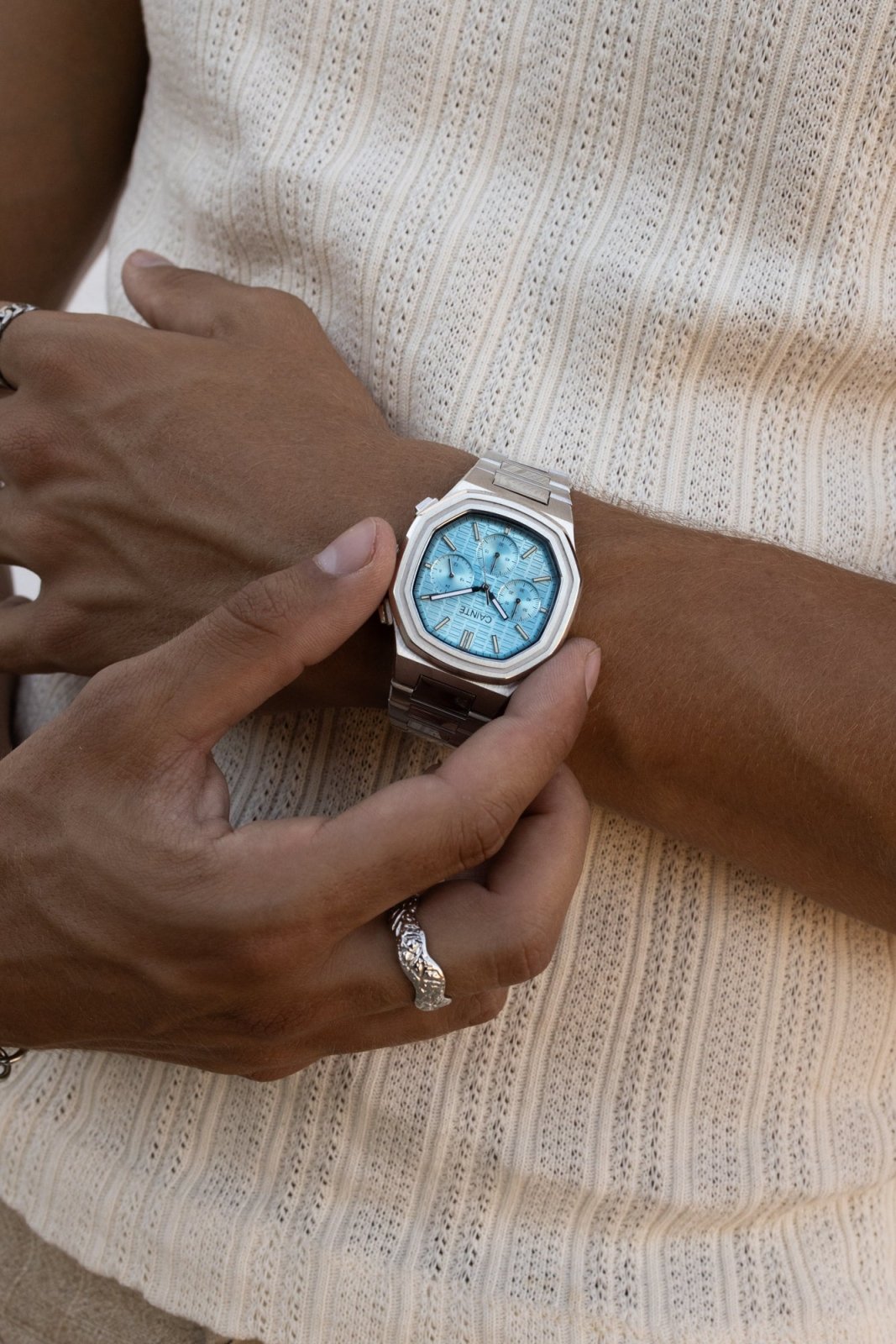 Hand adjusting the watch over a ribbed knit tank