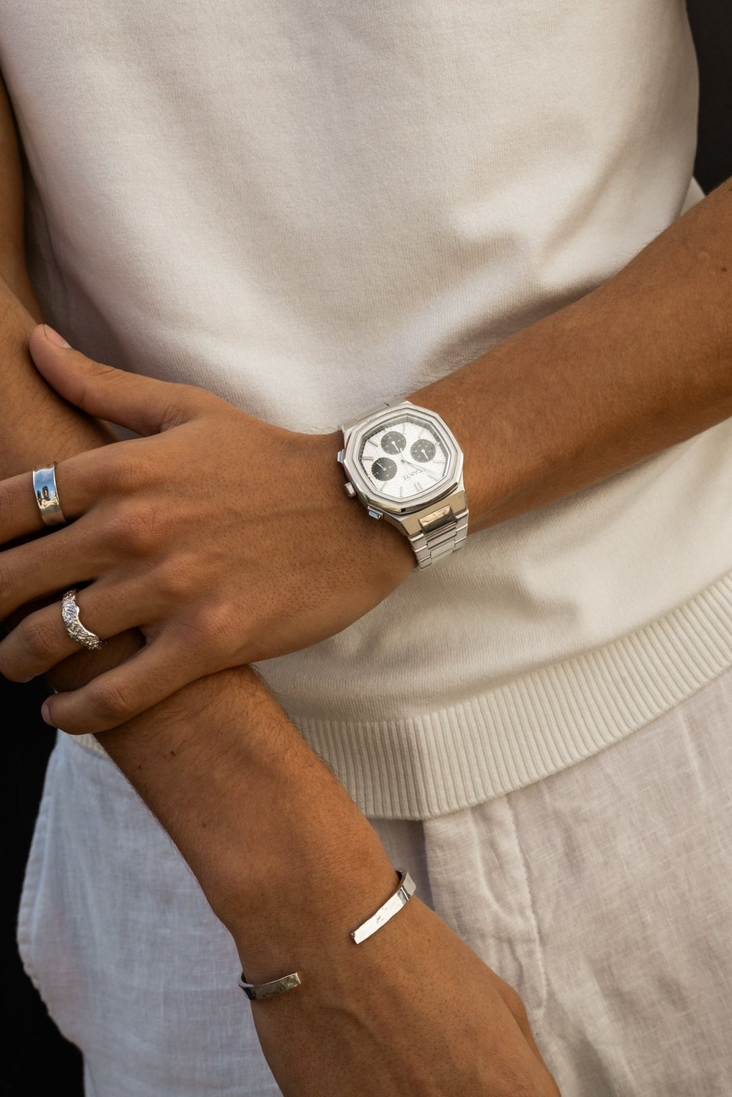 Arms crossed over a white T-shirt, watch on the wrist