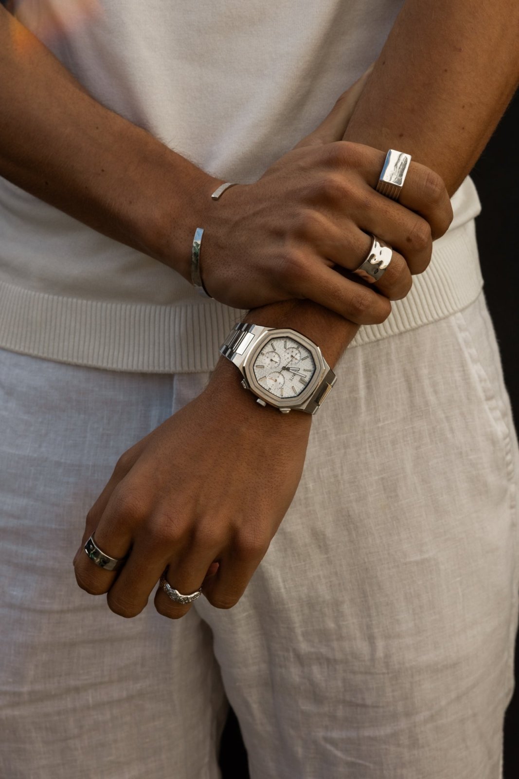 Arms crossed over a white T-shirt, watch on the wrist