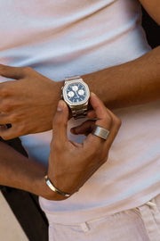 Hands adjusting the watch over a white T-shirt