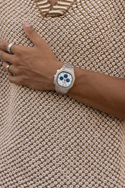 Wrist against a tan knit top, watch in view