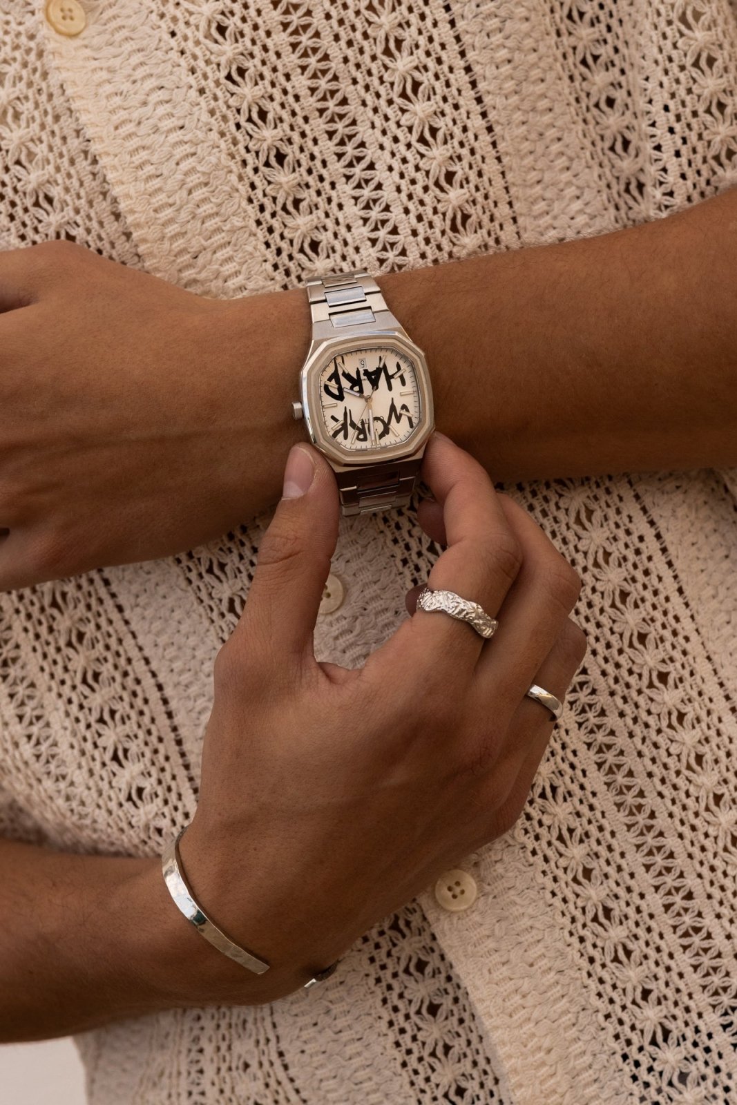 Hands adjusting the watch over a crochet shirt
