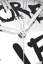 Macro view of the white dial with black graffiti lettering and polished hands
