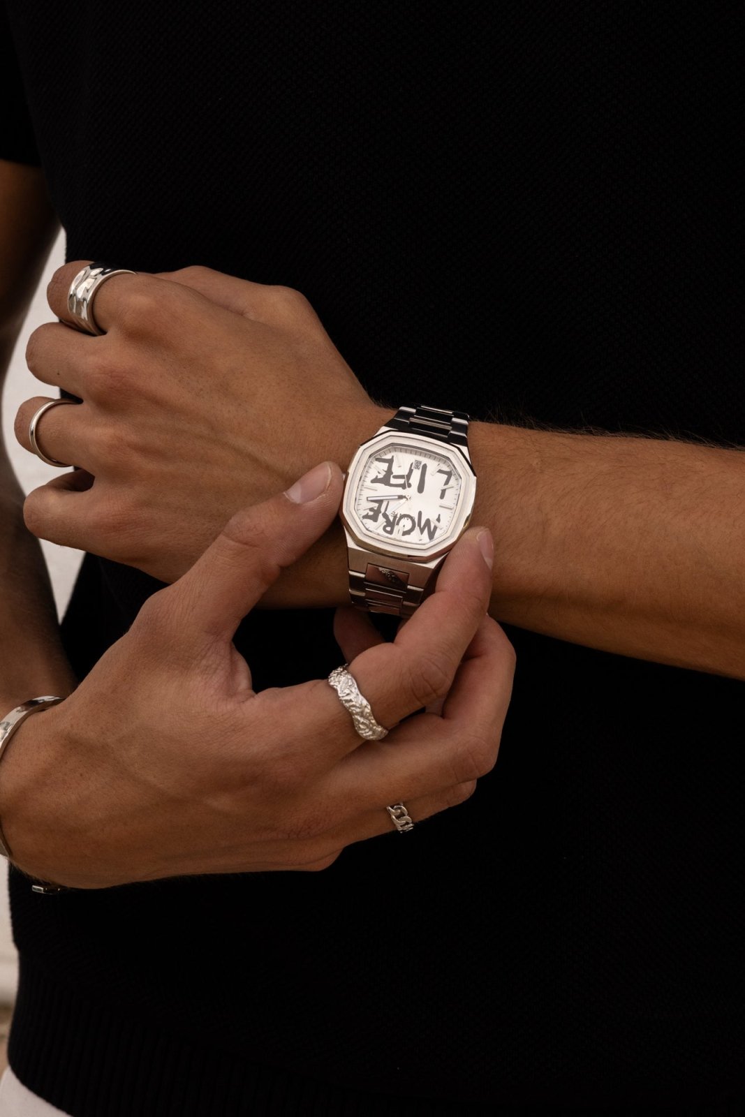 Hands adjusting the watch over a black top