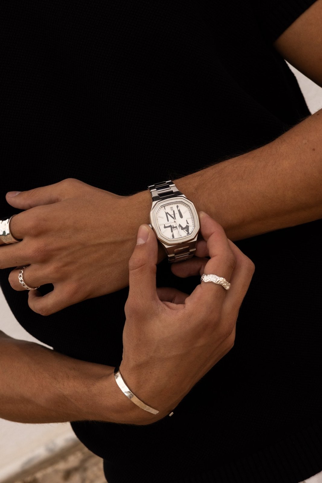 Hands adjusting the watch over a black top