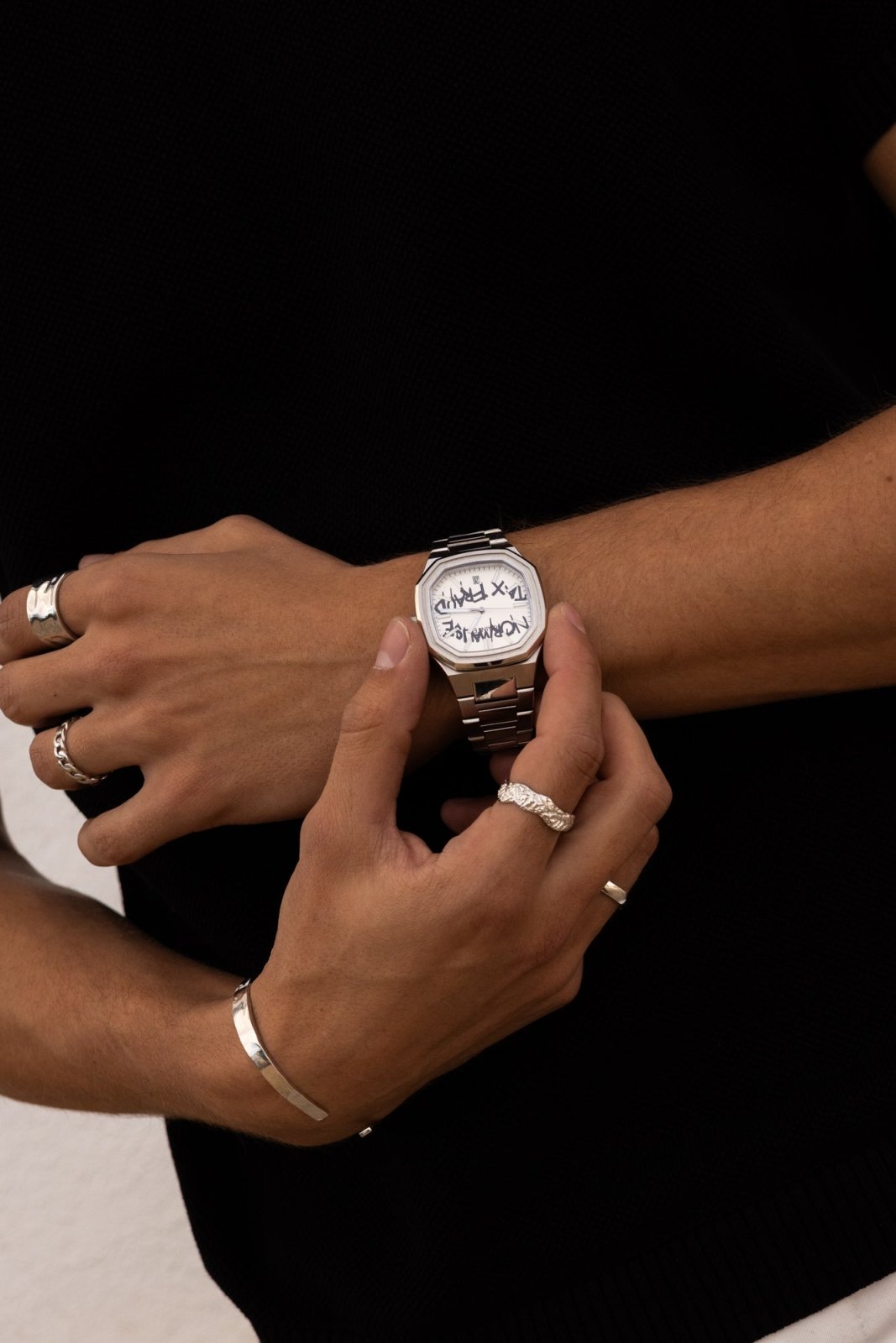 Hands adjusting the watch over a black top