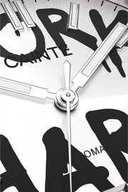 Macro view of the white dial with black graffiti lettering and polished hands