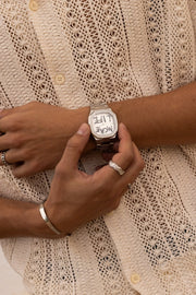 Hands adjusting the watch over a crochet shirt