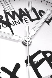 Macro view of the white dial with black graffiti lettering and polished hands