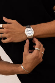 Hands adjusting the watch over a black top