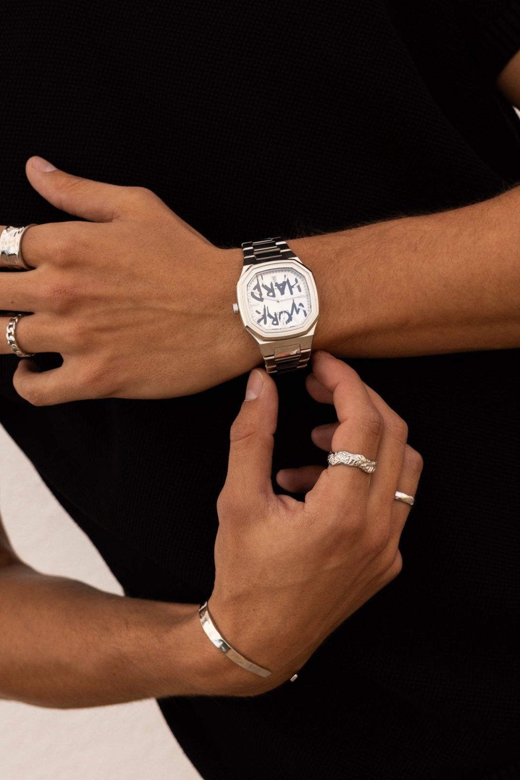Hands adjusting the watch over a black top