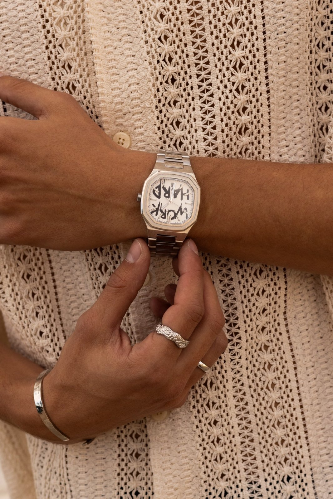 Hands adjusting the watch over a crochet shirt
