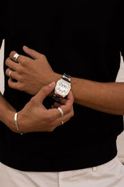 Hands adjusting the watch over a black top