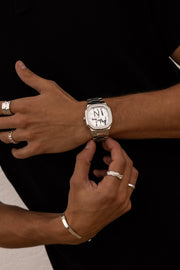 Hands adjusting the watch over a black top