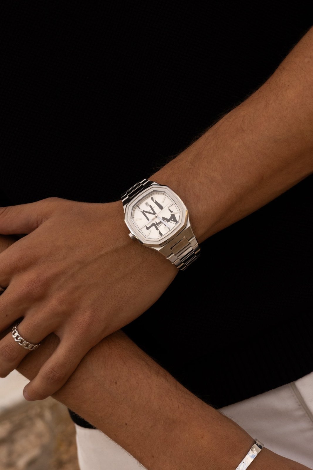 Arm across a black top, watch on the wrist