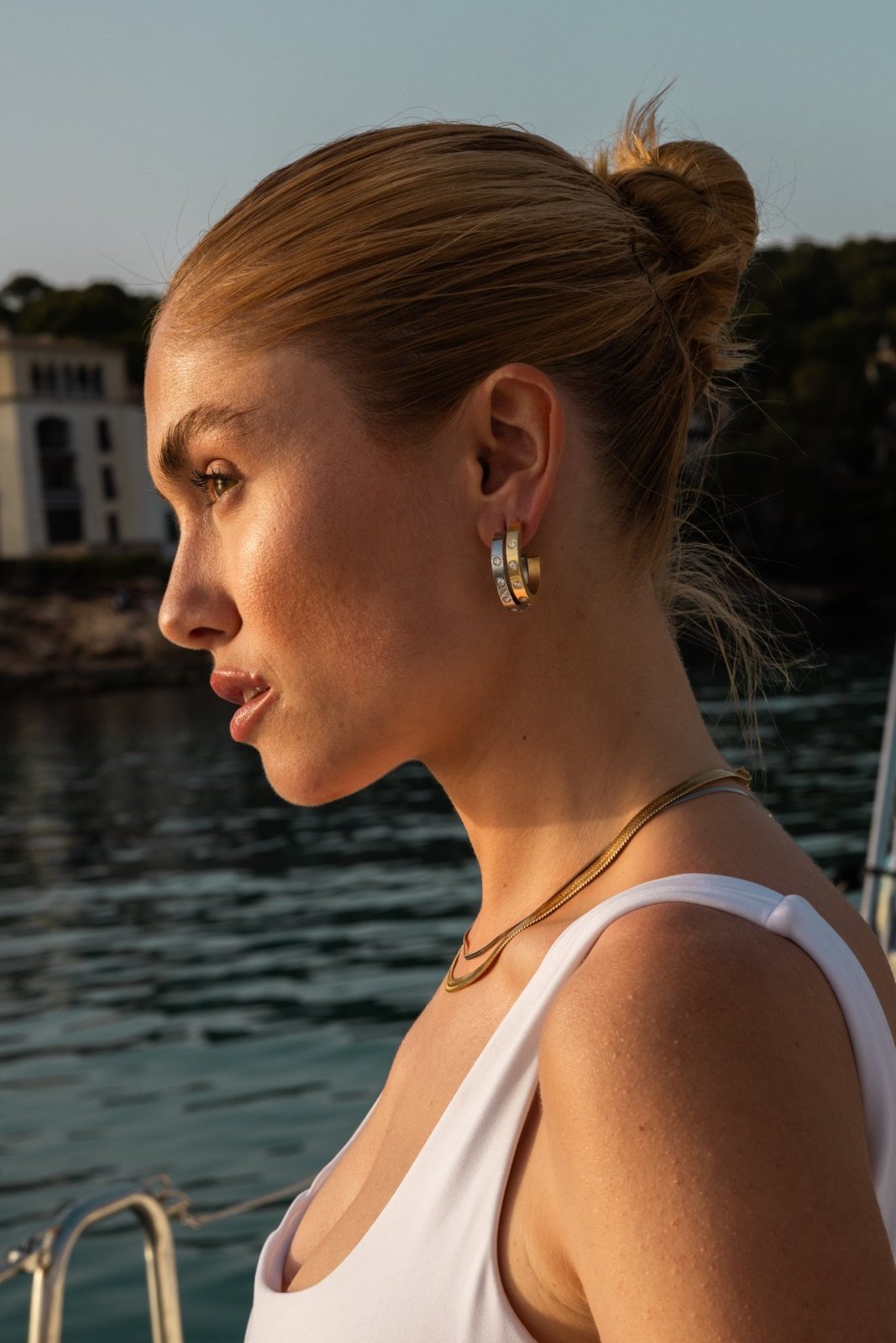 Model wearing the hoop earrings, profile by the water