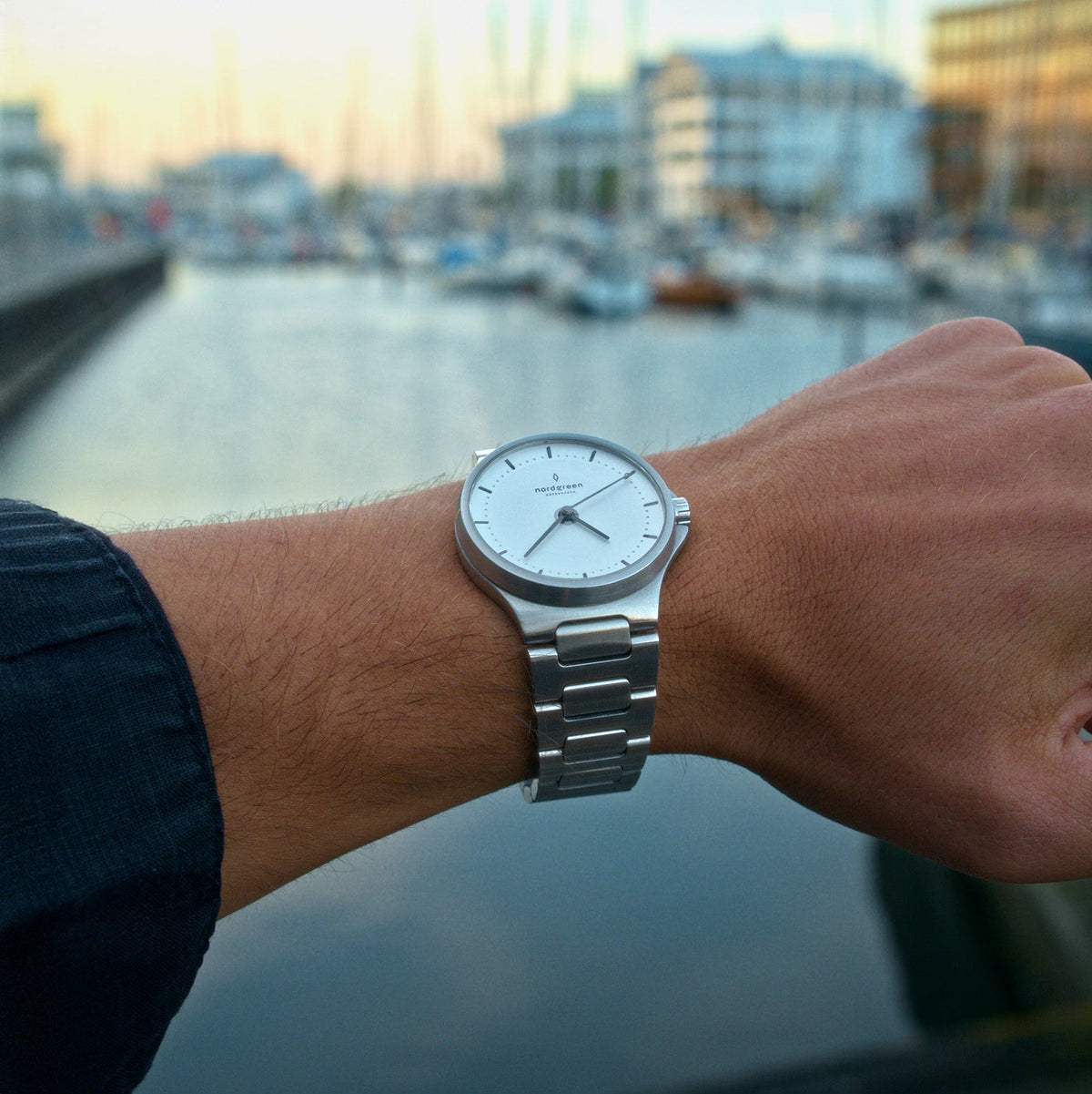 Wrist shot of the watch with a harbor and boats in the background.