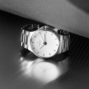 The watch resting on a dark perforated surface in low light.