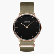 Watch with a black dial and rose gold-tone case on an olive green woven strap.