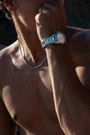 Hand raised to the face wearing the round watch