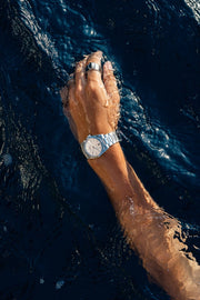 Arm reaching through the water wearing the watch