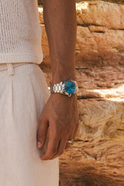 Arm by sunlit rocks with the turquoise watch on the wrist