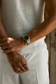 Arms crossed over a knit top, round watch on the wrist