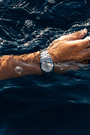 Arm in the water with the round watch on the wrist