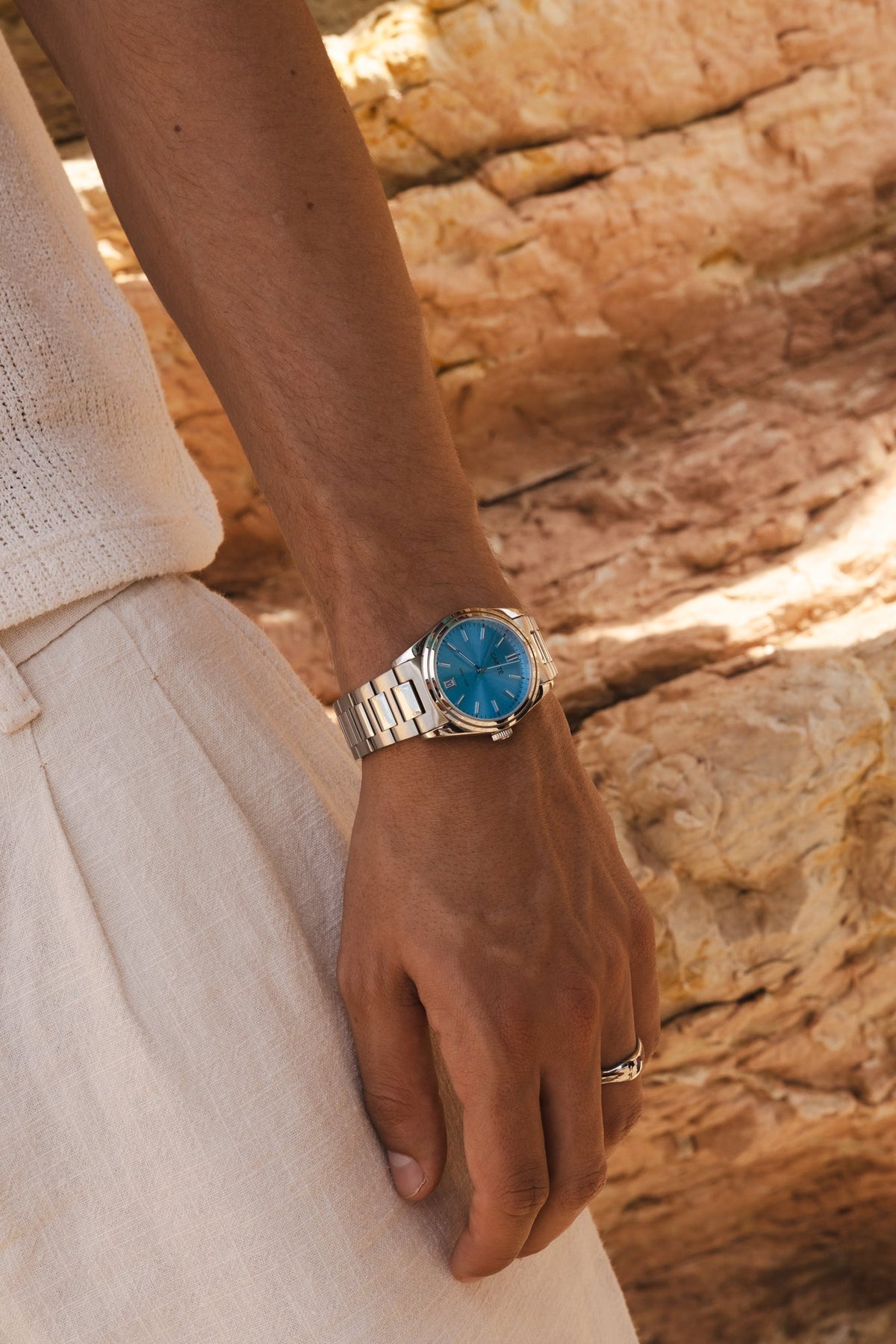 Wrist by sunlit rocks wearing the round watch