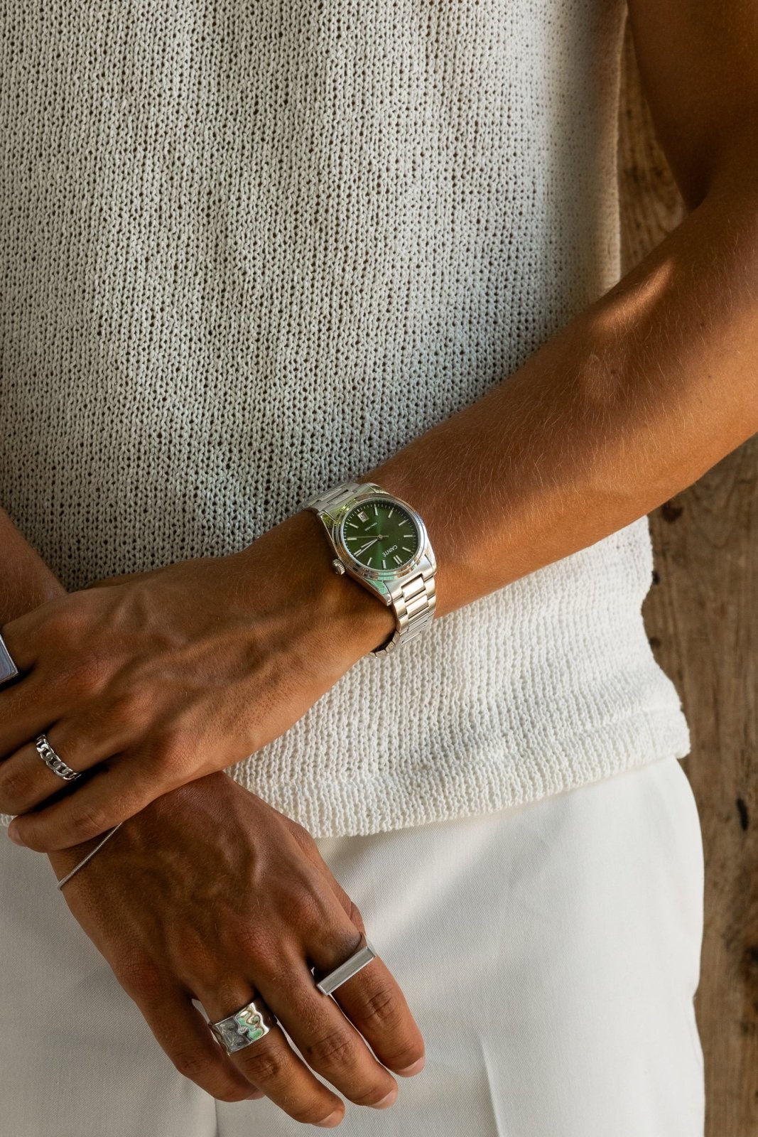 Arms crossed over a knit top, round watch on the wrist