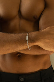 Silver-tone chain bracelet worn on the wrist with arms crossed