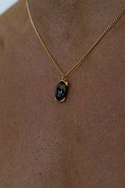 Gold-tone necklace with a black oval pendant, view 4 of 7