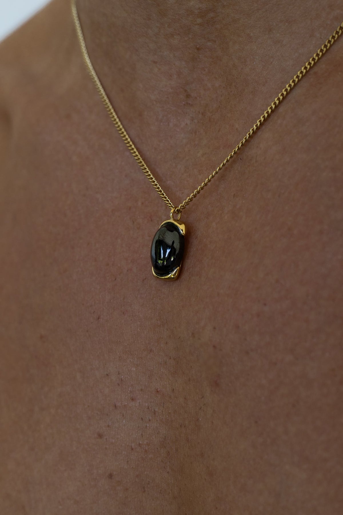 Gold-tone necklace with a black oval pendant, view 4 of 7