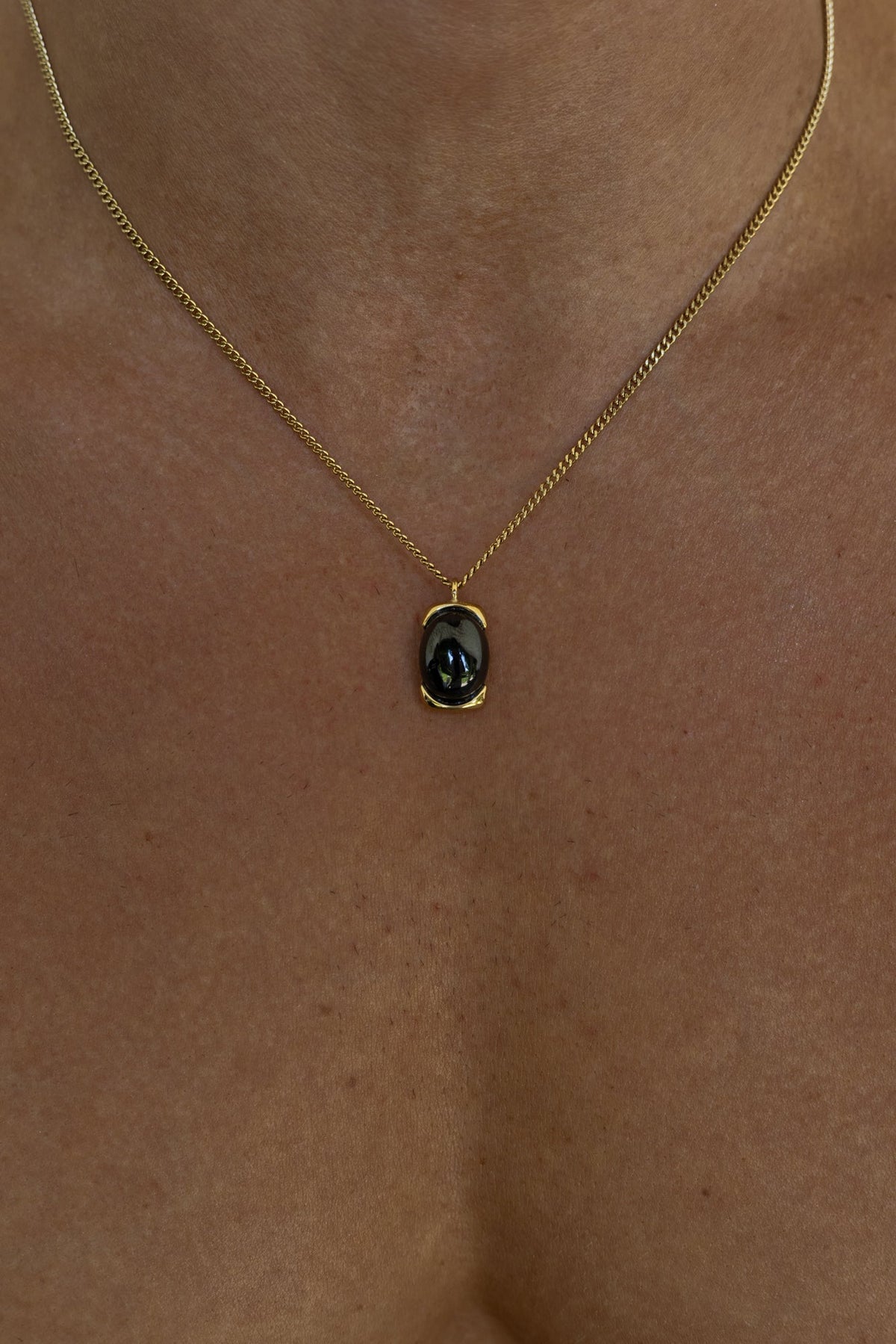 Gold-tone necklace with a black oval pendant, view 6 of 7