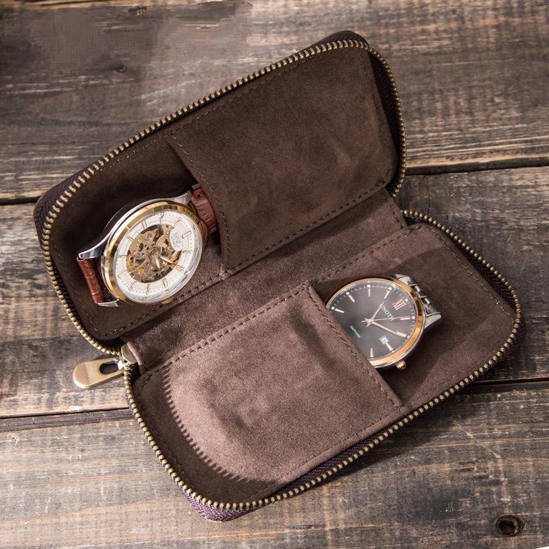 Open brown case on wood with two watches