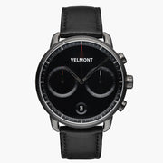 Chronograph-style watch with a black dial and gunmetal case on a black strap.