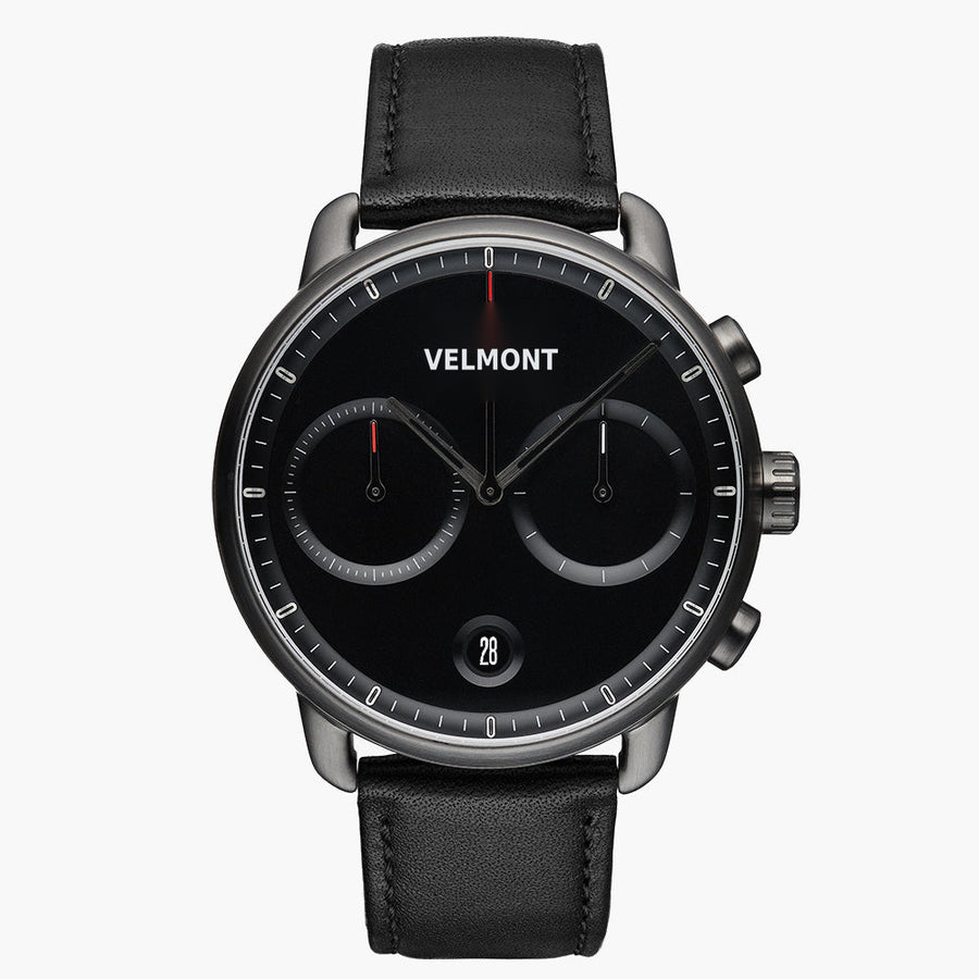 Chronograph-style watch with a black dial and gunmetal case on a black strap.