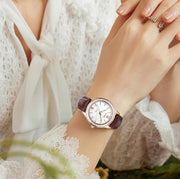 Rose gold-tone watch on a wrist by flowers