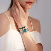 Green dial watch worn with a white top
