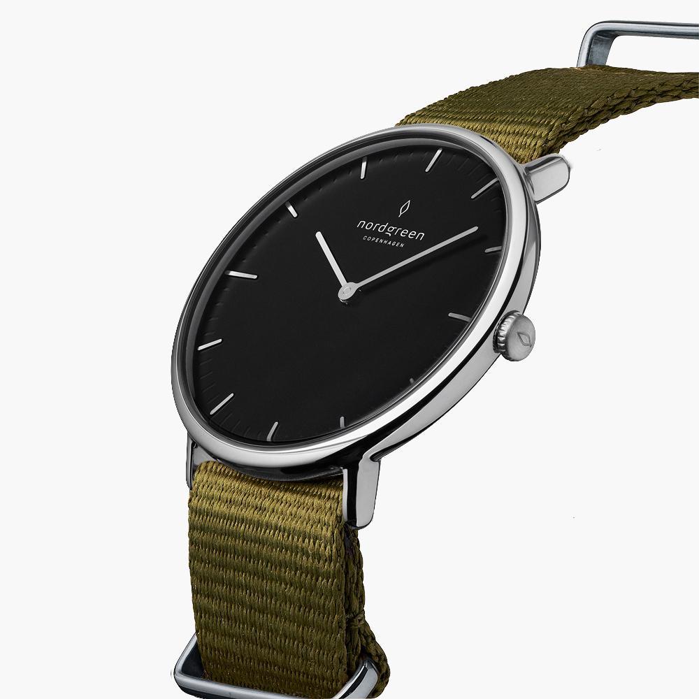 Angled view of the black dial and silver-tone crown on an olive woven strap.