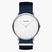 Minimalist watch with a white dial and silver-tone case on a navy woven strap.