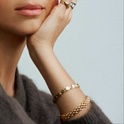 Watch-style link bracelet worn with a gray sweater