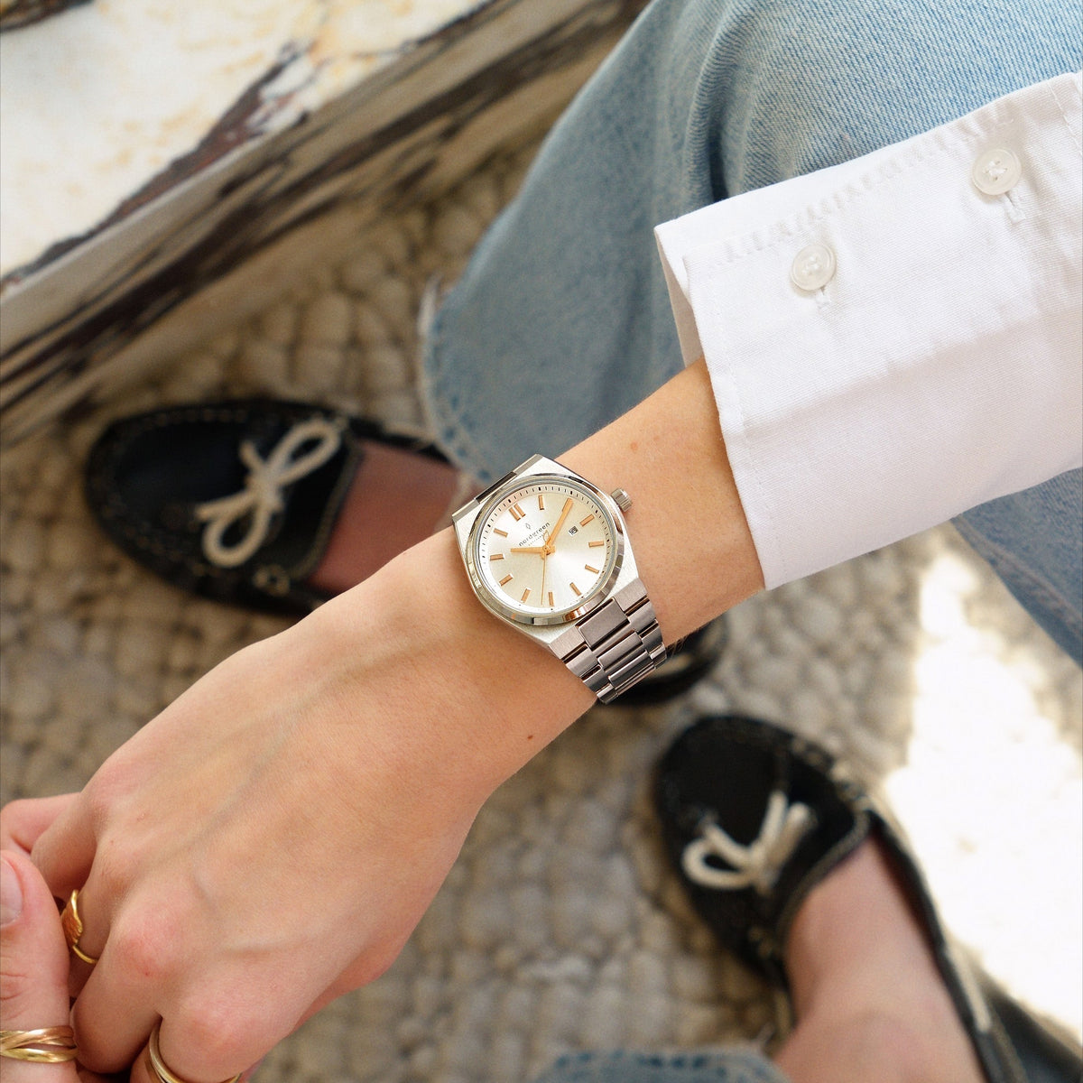 Worn with a white shirt cuff and jeans, black boat shoes in the background.