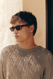 Man in a knit sweater wearing the tortoise sunglasses