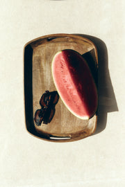 Tortoise sunglasses on a wooden tray next to watermelon