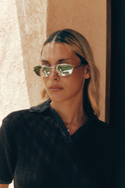 Woman wearing the mirrored sunglasses against a sandy wall